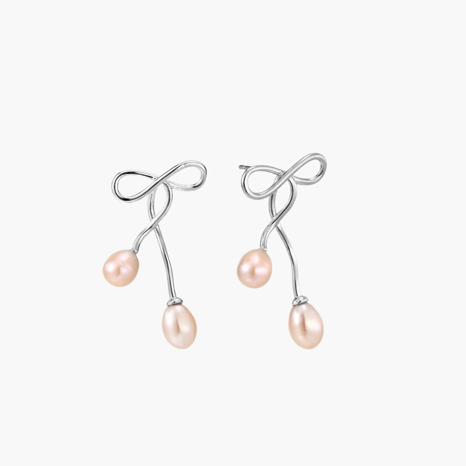 Rhodium-plated silver earrings with organic vine curves and two peachy freshwater pearls on cream background