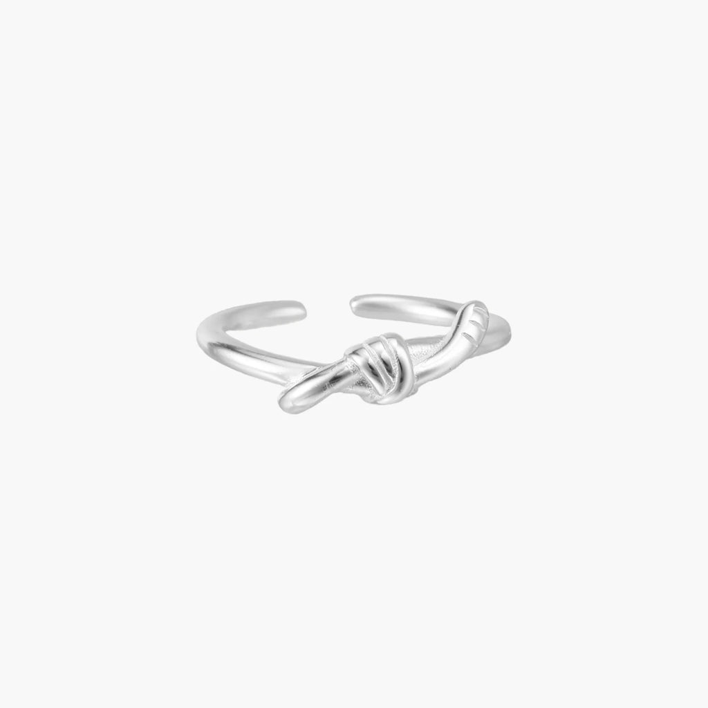Delicate rhodium-plated silver ring with elegant knot design on cream background, adjustable band style