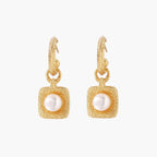 Pair of gold vermeil hoop earrings with textured square frames holding freshwater pearls on cream background