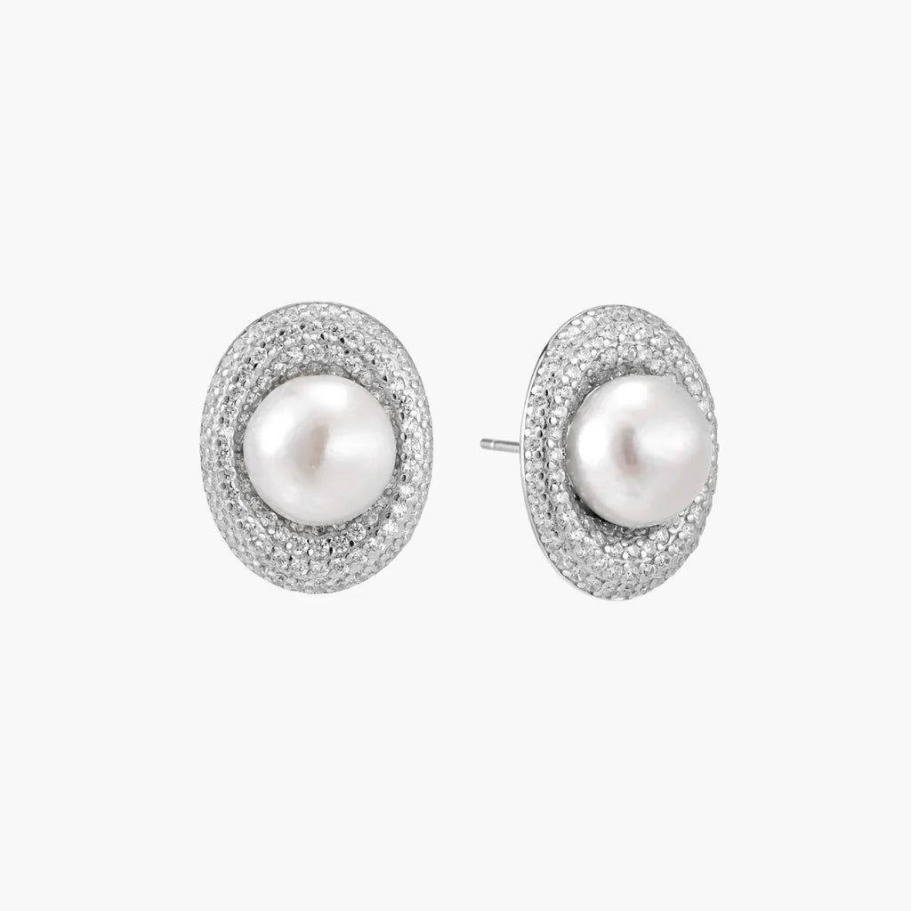 Oval rhodium-plated silver studs featuring freshwater pearls surrounded by pavÃ© crystal halo on white background