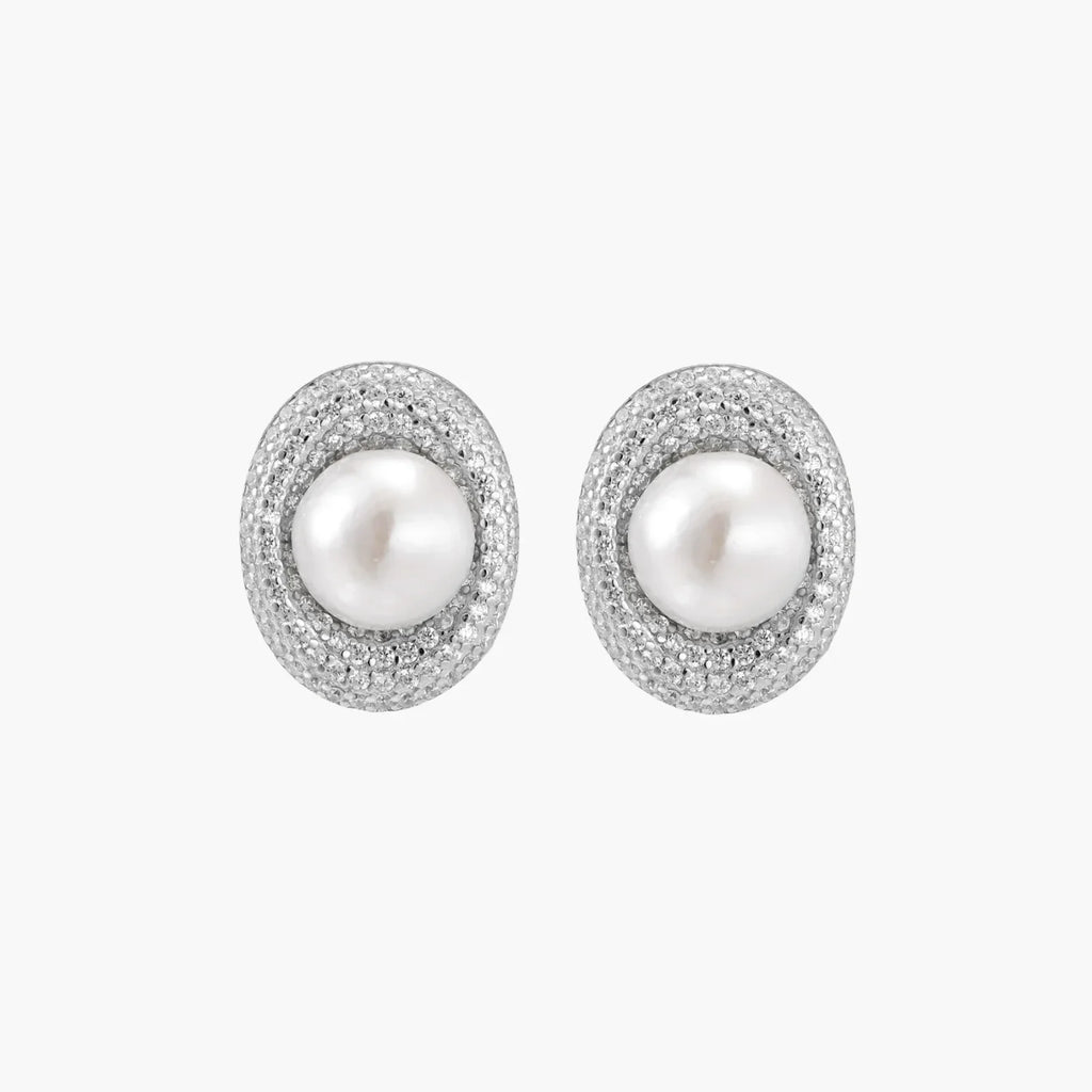 Oval rhodium-plated silver studs featuring freshwater pearls surrounded by pavÃ© crystal halo on white background