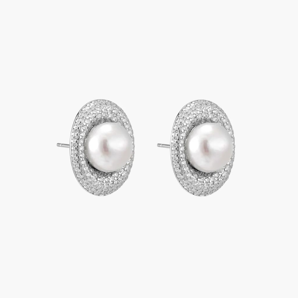 Oval rhodium-plated silver studs featuring freshwater pearls surrounded by pavÃ© crystal halo on white background