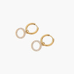 Gold-plated huggie hoop earrings with CZ-studded open circle charms on beige background