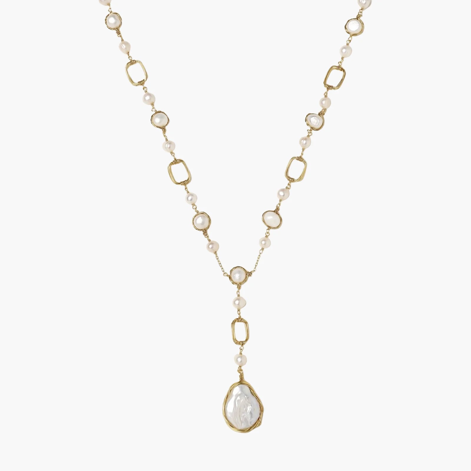 Y-shaped gold necklace with alternating geometric links, freshwater pearls, and baroque pearl pendant on cream background