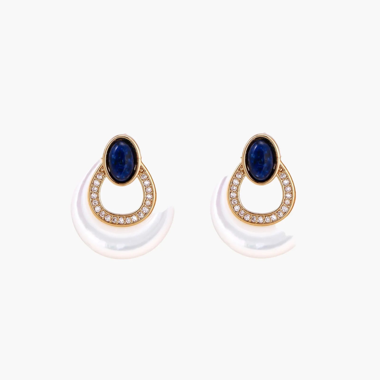 Gold drop earrings with oval lapis lazuli, crystal-paved frame, and iridescent mother-of-pearl teardrop on cream background