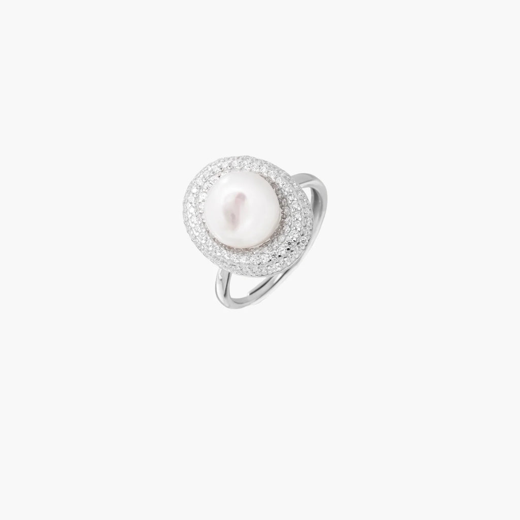 Silver ring with lustrous white pearl center surrounded by sparkling crystal halo on light background.