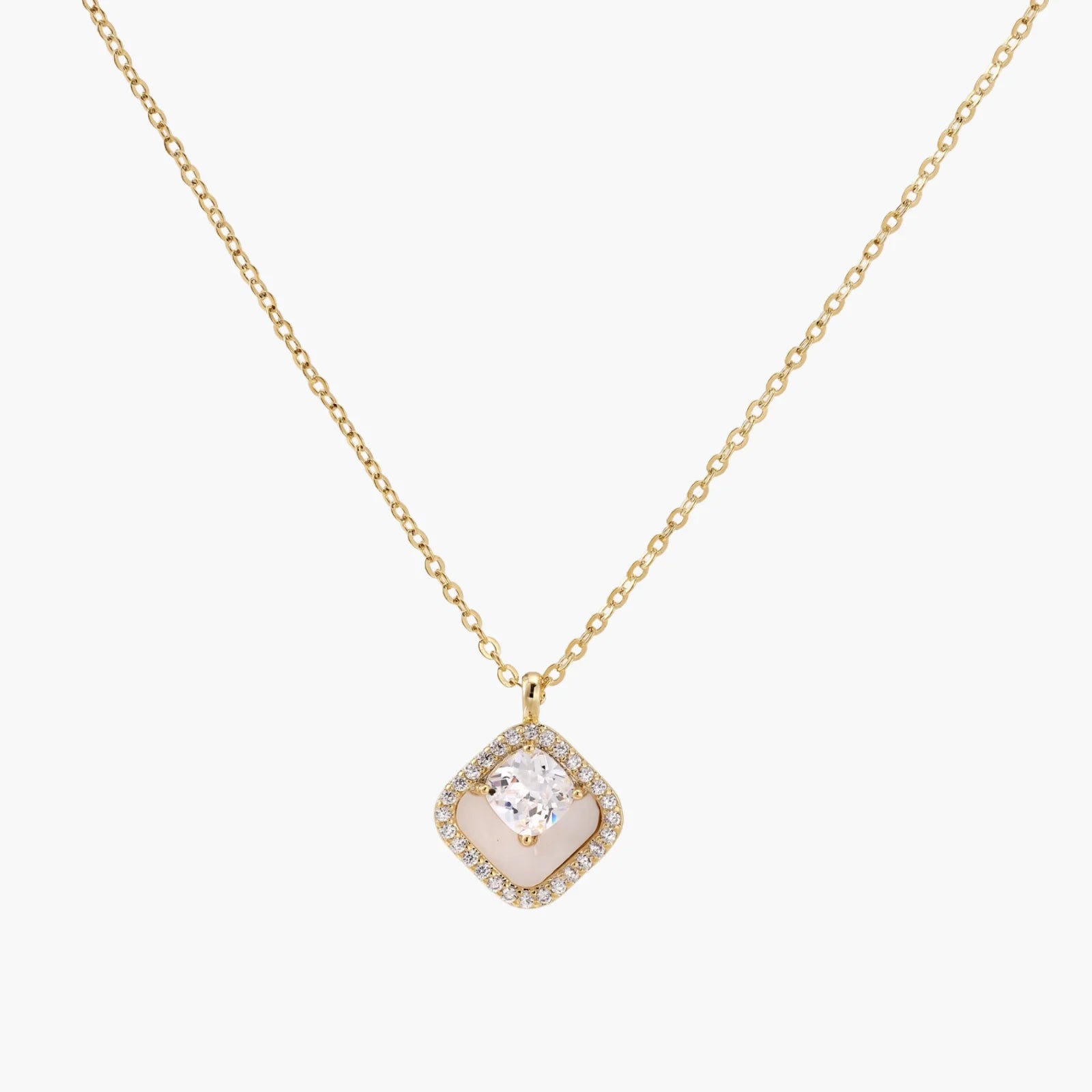 Gold quatrefoil pendant with crystal center on iridescent mother-of-pearl base, adjustable gold chain on cream background