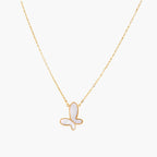 Gold-plated butterfly pendant with iridescent mother of pearl inlay on delicate chain against cream background.