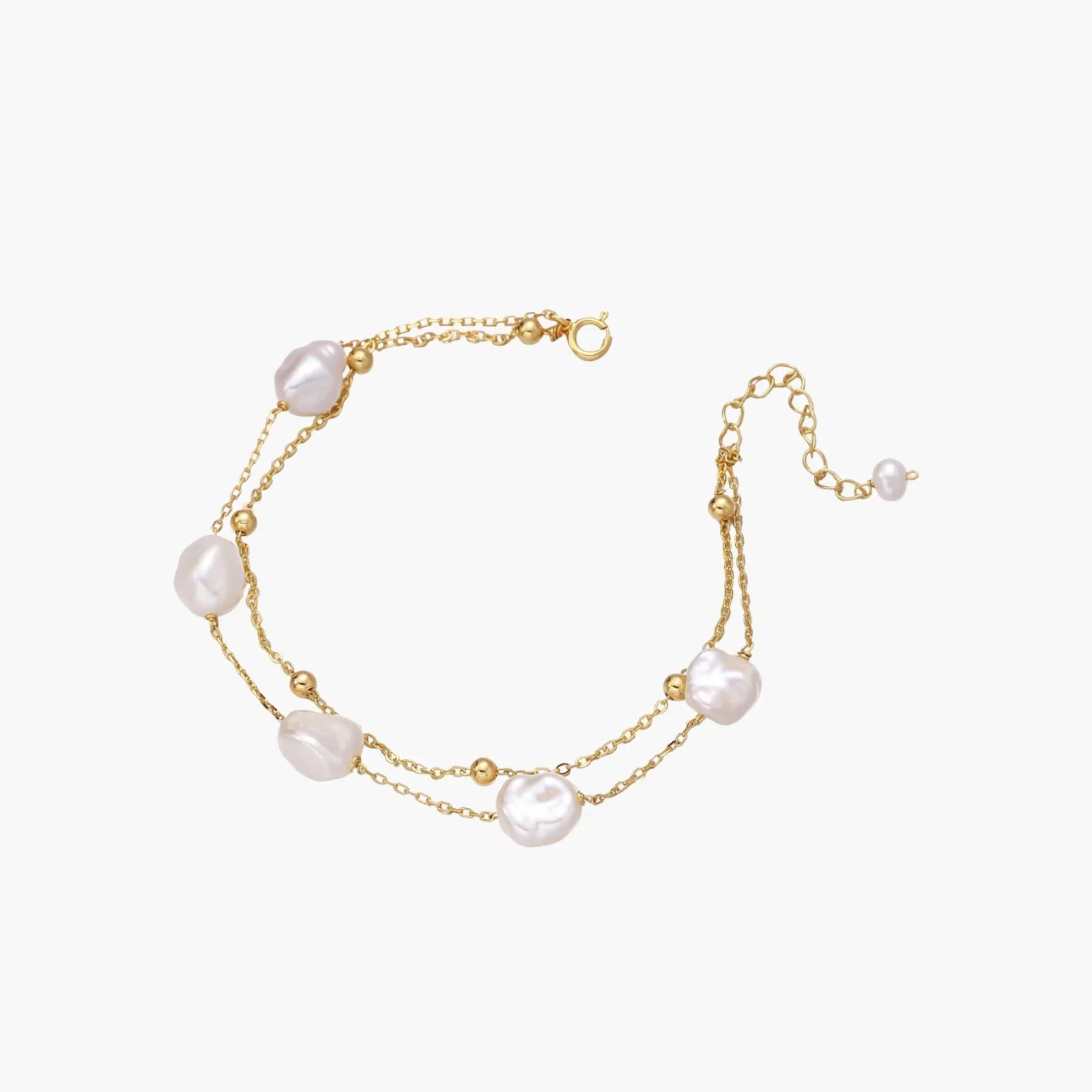 Double-strand gold bracelet with irregular baroque pearls and smooth freshwater pearls on cream background.
