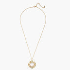 Gold pendant necklace with circular orbital design, iridescent mother-of-pearl center, and green zirconia accents