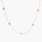 Gold vermeil chain with iridescent star-shaped baroque pearls and small round freshwater pearl drops on cream background.