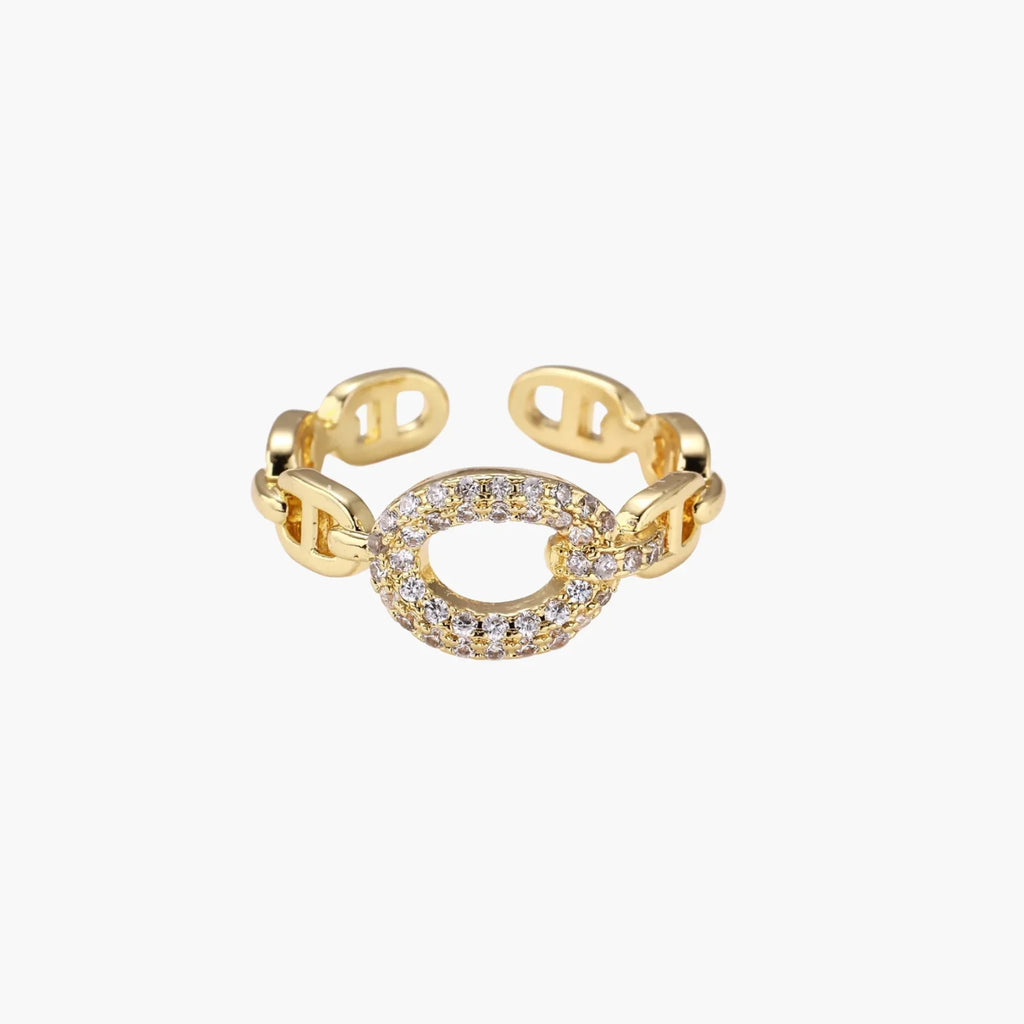 Gold-plated brass chain link ring with one oval CZ-pavÃ© segment on cream background, adjustable cuff style.