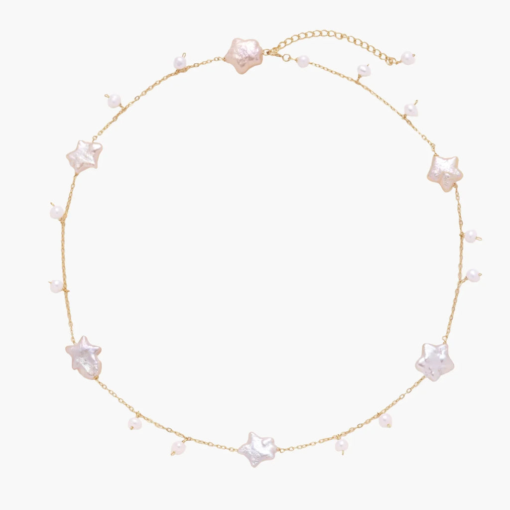 Gold vermeil chain with iridescent star-shaped baroque pearls and small round freshwater pearl drops on cream background.