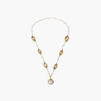 14K gold-plated necklace with eye-shaped stations and baroque pearl pendant on cream background
