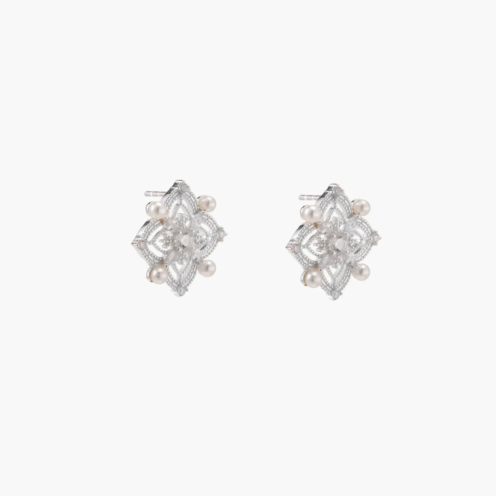Ornate sterling silver stud earrings with mandala-inspired filigree pattern and four freshwater pearls on beige background
