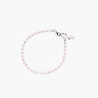Delicate freshwater pearl bracelet with rhodium-plated silver clasp and single pearl drop charm on cream background