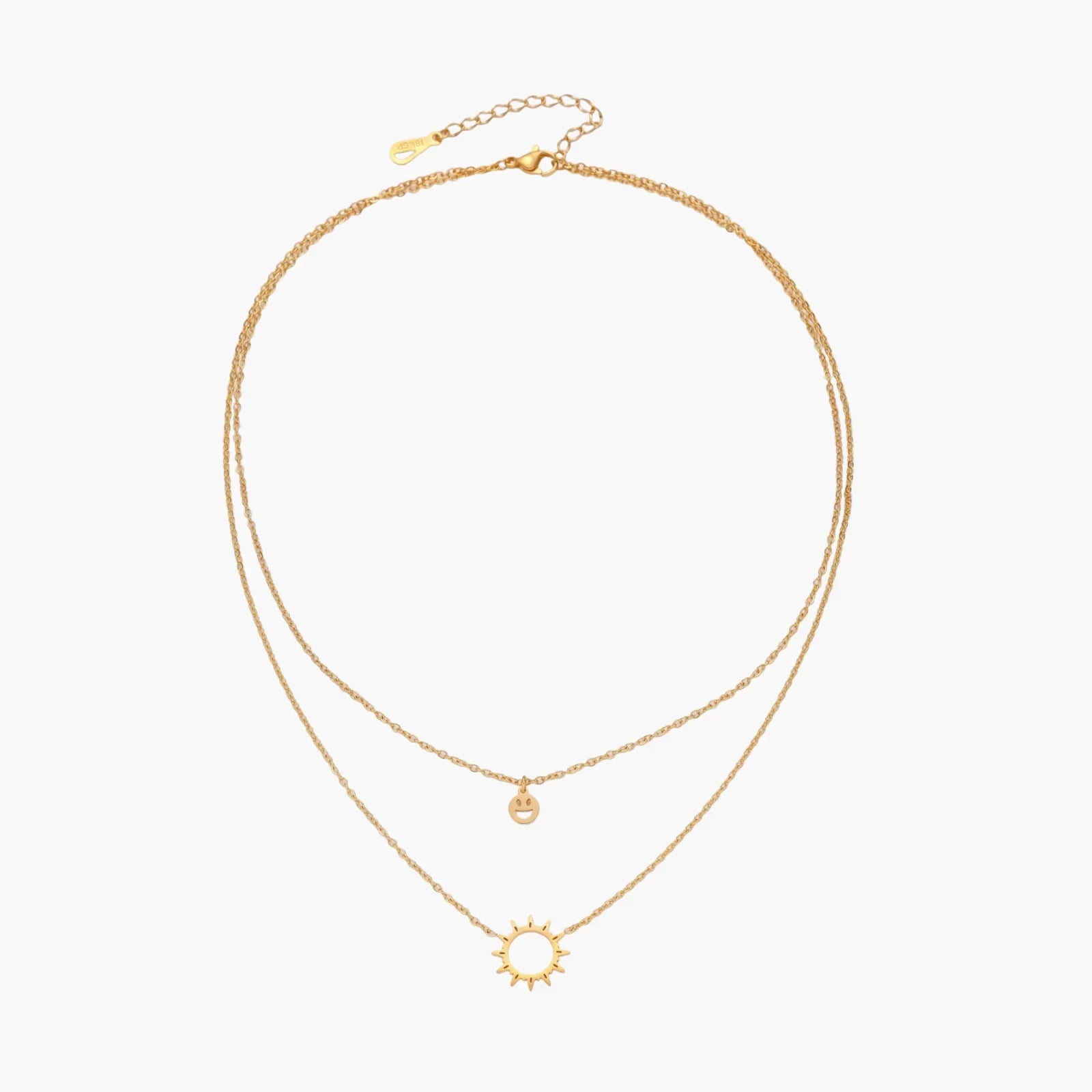 Gold layered necklace set with sunburst and smiley face pendants on delicate chains against white background.