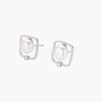 Rhodium-plated silver stud earrings with cushion frame, centered freshwater pearl, and tiny crystal accent