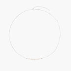 Delicate sterling silver chain necklace with small freshwater pearls arranged in a curved smile arc on cream background.