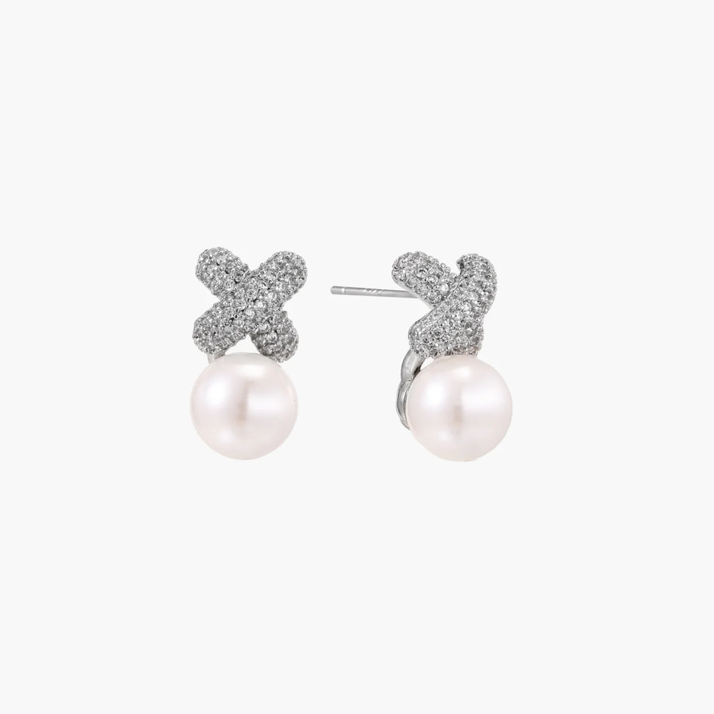 White gold plated studs featuring pavÃ© X-shaped tops with freshwater pearl drops on cream background.