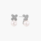 White gold plated studs featuring pavÃ© X-shaped tops with freshwater pearl drops on cream background.