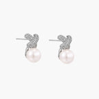 White gold plated studs featuring pavÃ© X-shaped tops with freshwater pearl drops on cream background.