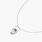 Whimsical owl pendant holding a white pearl on a gold swing, rhodium-plated silver chain on cream background.
