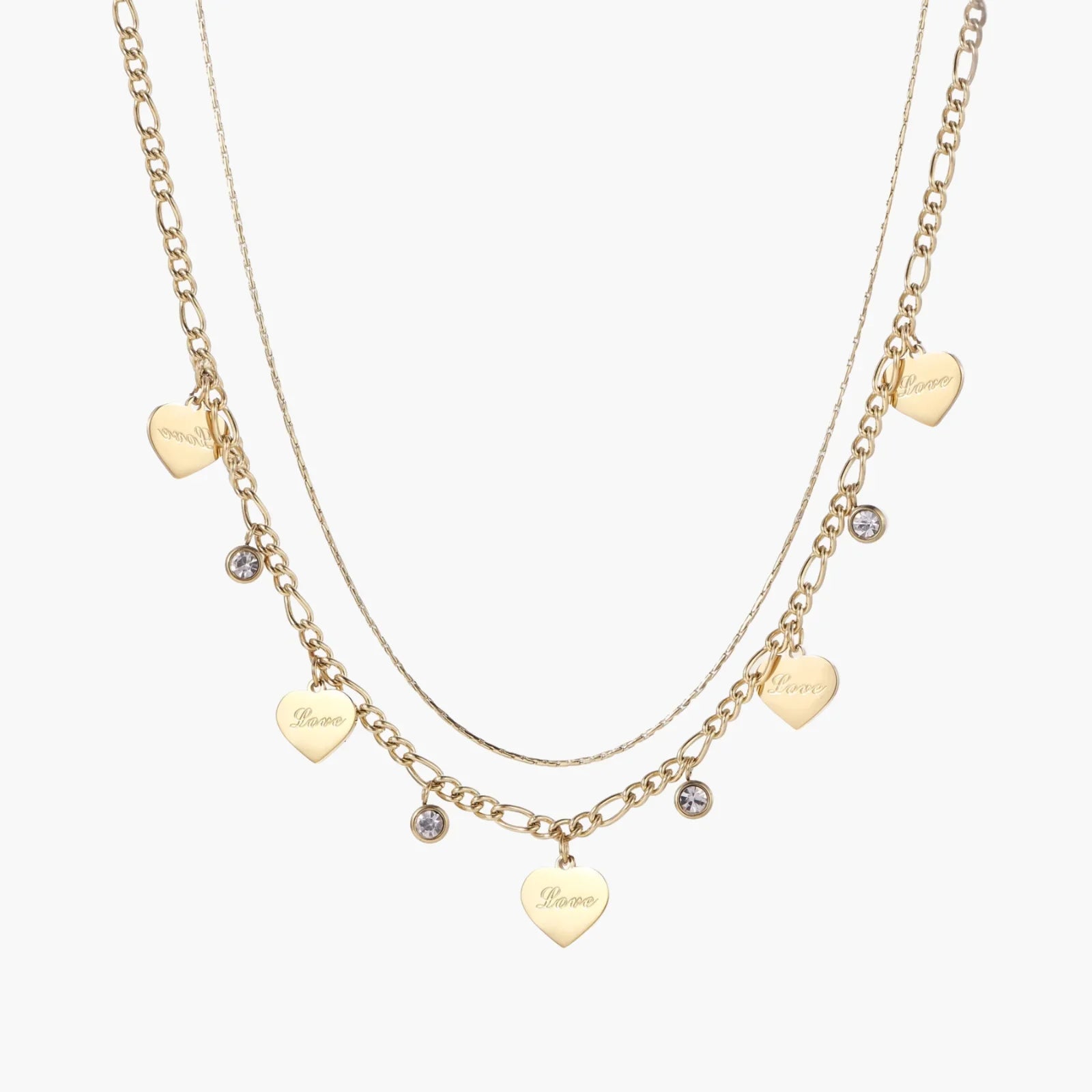 Gold layered necklace set with engraved heart pendants and crystal accents on cream background