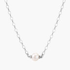 Dainty rhodium-plated silver chain necklace with centered 10mm freshwater pearl and crystal accents on cream background