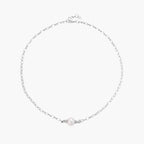 Dainty rhodium-plated silver chain necklace with centered 10mm freshwater pearl and crystal accents on cream background