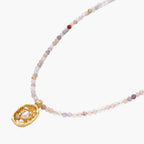 Delicate gold-plated necklace with mixed gemstone beads and ornate oval pendant on white background