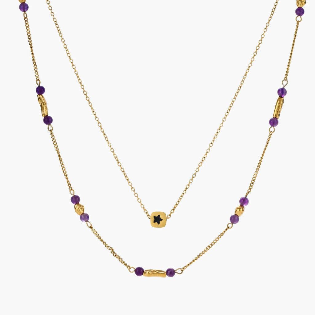 Two layered gold-tone necklaces with purple stone beads and star pendant against cream background.