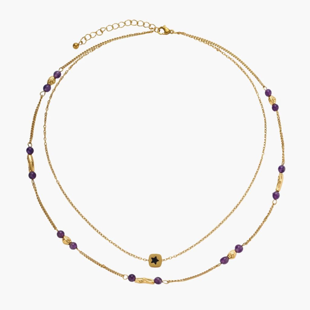 Two layered gold-tone necklaces with purple stone beads and star pendant against cream background.
