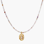 Delicate gold-plated necklace with mixed gemstone beads and ornate oval pendant on white background