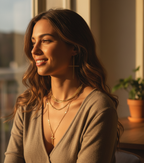 Woman wearing layered gold necklaces in a warm indoor setting