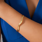 Gold bracelet on a person's wrist with a white background